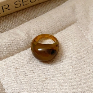 Macro shot of an amber resin dome ring with tortoiseshell patterns on beige linen fabric