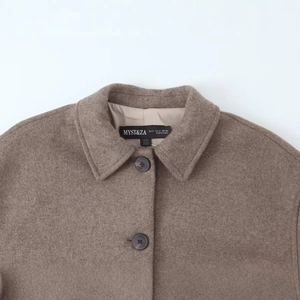 Deep camel wool blend short coat showing lapel and button detail on light grey backdrop