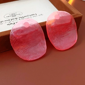 Detail showing shell-textured pink resin earrings with a unique pearlescent finish