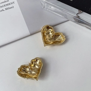 Detail of gold heart stud earring with unique lava texture and hammered metal surface