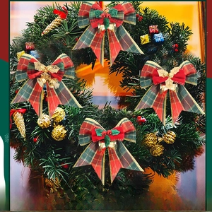 Close-up of red and green plaid Christmas bows with gold bells on festive wreath