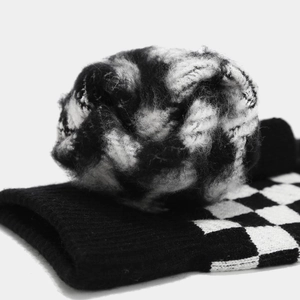 Macro de la texture en tricot damier avec détail de pompon en peluche noir et blanc