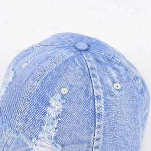 Detail of distressed light blue denim baseball cap featuring vintage washed fabric and stitching