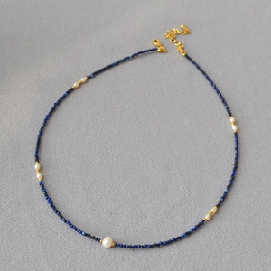 Detailed view of faceted lapis lazuli beads and tiny rice pearls on a thin beaded necklace