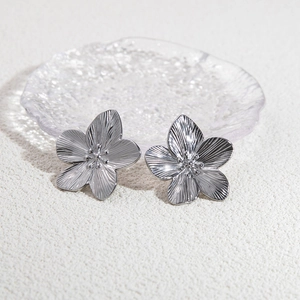 Macro view of silver flower stud earrings with detailed 3D texture and metallic luster
