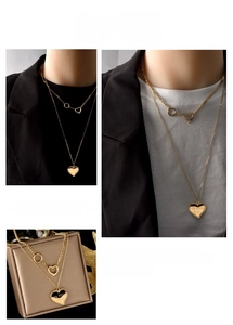 Close-up of double-layered gold titanium necklace with heart charms and engraved details