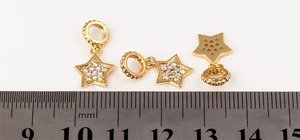 Detail shot of 15mm gold-plated star pendants with micro-pave crystals on a scale