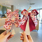 Close-up of children cherry print sequin bow hair clips held in hand for hair styling