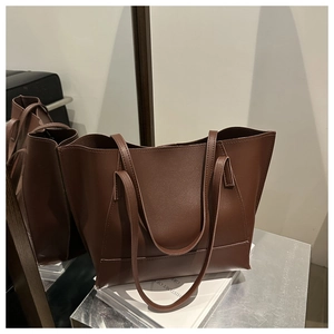 Grande borsa tote in pelle marrone esposta su libri con dettaglio di riflesso nello specchio