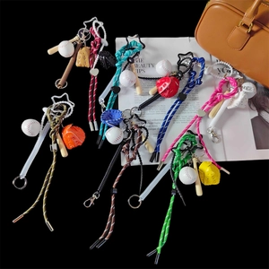 Dettaglio di portachiavi da baseball colorati con mini mazza e guanto su borsa di pelle