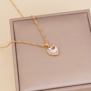 Golden heart pendant necklace with clear zircon stones on a beige jewelry display box