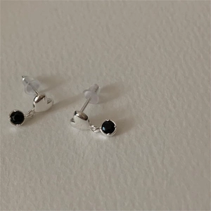 Minimalist 925 sterling silver heart earrings with black stones on a textured background