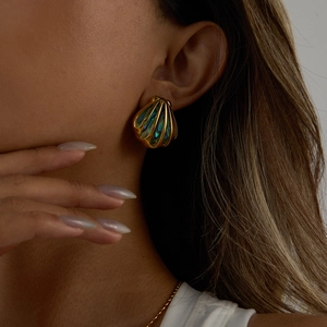 Close-up of golden shell earrings with colorful abalone shell inlay worn by a model