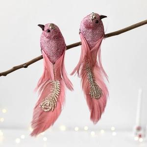 Oiseaux de Noël roses en plumes avec paillettes et sequins sur branches rustiques
