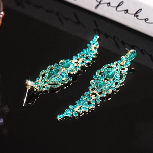 Detail of luxury emerald green teardrop crystals and gold tassels on dangling earrings