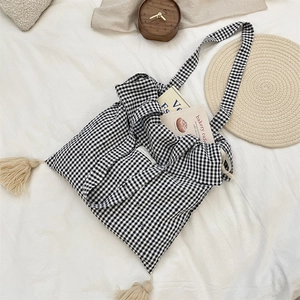 Dettaglio borsa tote in tela a scacchi bianchi e neri con nappine beige e chiusura a coulisse
