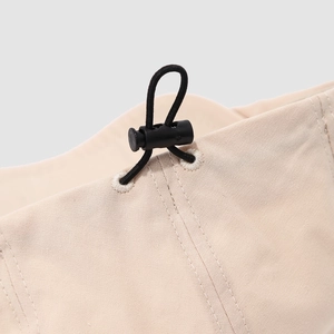 Detalle del cordón ajustable negro y el cierre de plástico en la gorra de lona beige