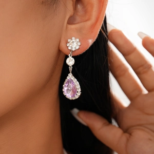 Close-up of purple teardrop crystal earrings worn by a model in a luxury palace style