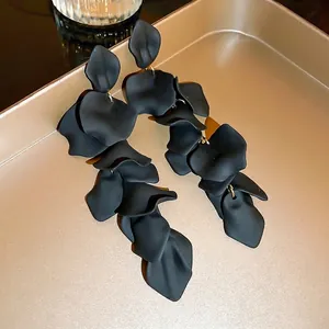 Long matte black flower petal tassel earrings with elegant gold hooks on tray