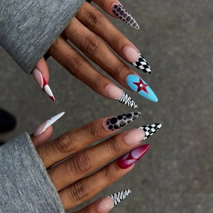 Detail of almond stiletto press-on nails with leopard, checkerboard, and star patterns