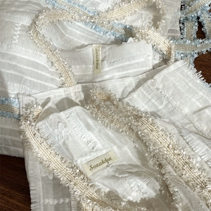 Détail du sac en toile avec sangle florale, franges texturées et étiquette Sozakka