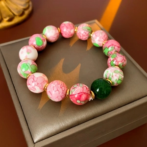 Detailed close-up of pink and green ceramic beads with gold-plated metal spacers on a display