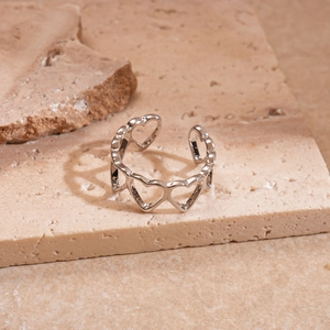 Detail of silver hollow heart pattern open ring casting a heart shadow on sandstone