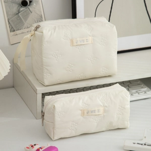 Detail of cream white quilted makeup bags with 3D butterfly texture and two-piece set design