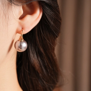 Close-up of a vintage round pearl earring in gold on a model for a chic french style