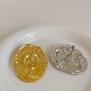 Broches vintage dorées et argentées avec visage en relief sur plat en céramique blanche