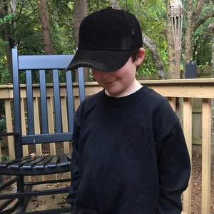Distressed black baseball cap and sweatshirt set worn by child model in outdoor setting