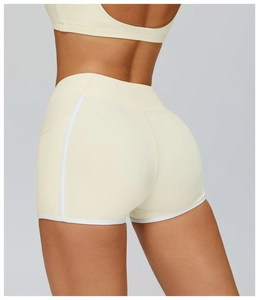 Close-up of cream high-waisted yoga shorts with white contrast piping and bodycon fit