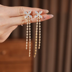 Dettaglio di orecchini a farfalla con nappa placcati in oro 18K con zirconi tenuti in mano