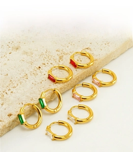Detail of colorful rectangular zircon inlay on golden stainless steel hoop earrings