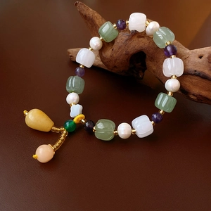 Detail of beaded jade flower bracelet with colorful stones and tassel on dark wood