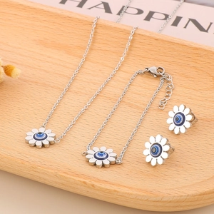 Detailed set of silver daisy jewelry with blue evil eye charms on a wooden tray