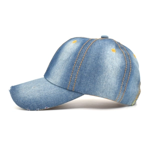 Close-up of distressed blue denim baseball cap featuring vintage washed texture and yellow stitching