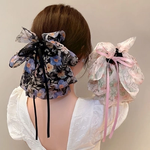 Detailed view of floral bow hair claw clips with streamers on a model's ponytail