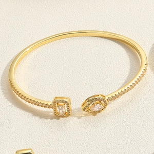 Macro detail of gold-plated bangle featuring teardrop and square cut zircon stones