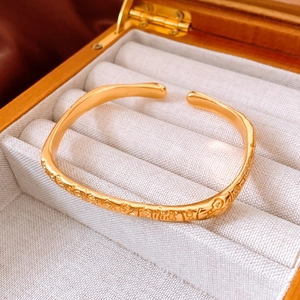Vue macro du bracelet jonc doré mat avec motifs de caractères Fu chinois en relief