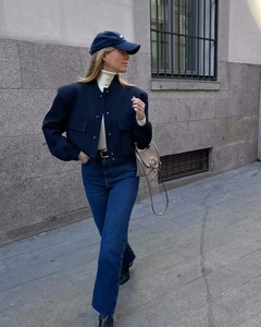 Deep blue short jacket with utility pockets paired with blue jeans and beige bag