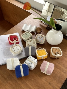 Flat lay of colorful cotton linen tech accessory pouches with zippers and metal rings
