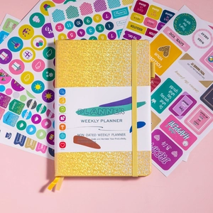 Flat lay of yellow glitter weekly planner with colorful decorative stickers for goal setting