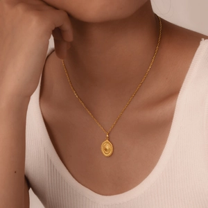 Detail of vintage gold oval sunray pendant necklace worn on neck by a model