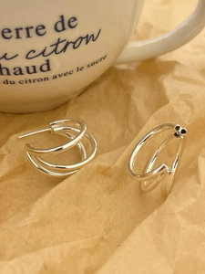 Close-up of S925 sterling silver triple hoop earrings on textured paper background