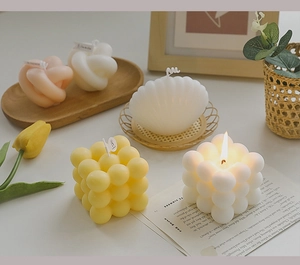 Cozy aesthetic view of bubble cube, shell, and knot scented candles on a wooden tray