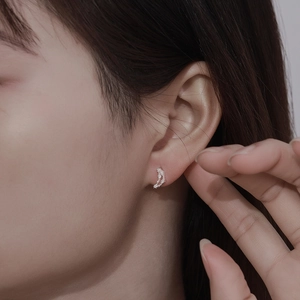 Close-up of crescent 999 sterling silver stud earring with white cubic zirconia stones
