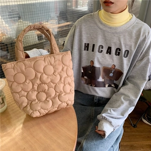Quilted floral handbag in beige, shown in a cozy cafe setting for casual lifestyle use