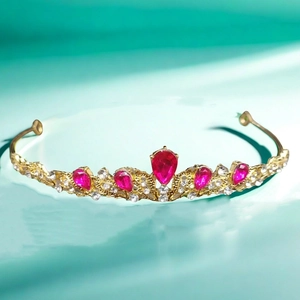 Close-up of golden bridal tiara with sparkling rhinestones and drop-shaped red crystals