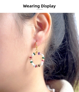 Close-up of a model wearing colorful beaded hoop earrings with gold hooks and pearls
